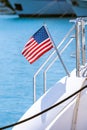 The flag of the United States flutters in the wind on a stainless steel flagpole at the stern of a motor yacht. Marina in the port Royalty Free Stock Photo