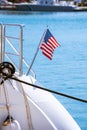 The flag of the United States flutters in the wind on a stainless steel flagpole at the stern of a motor yacht. Marina in the port Royalty Free Stock Photo