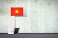 Flag of Vietnam, on a stick, in a small bucket, against the background of a concrete wall. Copy space. Signs and Symbols