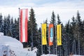 The flags of: Austria, Planai, Ski Amade, Hochwurzen at the ski region Schladming Dachstein with trees at the background. Royalty Free Stock Photo