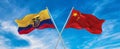 flags of China and Ecuador waving in the wind on flagpoles against sky with clouds on sunny day. Symbolizing relationship, dialog