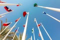 Flags of different countries of world flutters in wind background of blue sky. Bottom up view Royalty Free Stock Photo