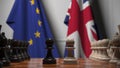 Flags of the EU and the UK behind chess board. The first pawn moves in the beginning of the game. Brexit related