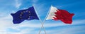 flags of European Union and Bahrain waving in the wind on flagpoles against sky with clouds on sunny day. Symbolizing relationship