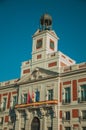 Flags on exquisite old building with bell tower and clock in Madrid