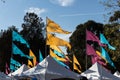 Flags flying atop carnival tents against blue sky