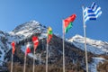 Flags of Greece, Belarus, Lithuania and other countries wave in the wind as a friendship symbol on snowy mountains peak and blue s