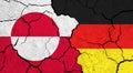 Flags of Greenland and Germany on cracked surface