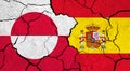 Flags of Greenland and Spain on cracked surface