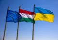 Flags of Hungary Ukraine and European Union waving on pole against blue sky Royalty Free Stock Photo