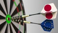 Flags of Japan and the European Union on darts hitting bullseye of the target. International cooperation or competition Royalty Free Stock Photo