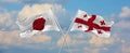 flags of Japan and Georgia waving in the wind on flagpoles against sky with clouds on sunny day. Symbolizing relationship, dialog
