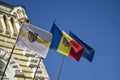 Flags of Moldova, European Union and city of Chisinau are fixed on facade of old municipal building against blue sky. Chisinau