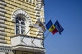 Flags of Moldova, European Union and city of Chisinau are fixed on facade of old municipal building against blue sky. Chisinau