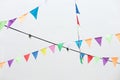 Flags multicolored birthday decoration. Colorful bunting flags hanging on white wall. Wedding decor. Royalty Free Stock Photo