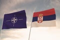 Flags of NATO and SERBIA waving with cloudy blue sky background,3D rendering WAR