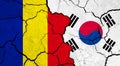 Flags of Romania and South Korea on cracked surface