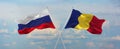 flags of Russia and romania waving in the wind on flagpoles against sky with clouds on sunny day. Symbolizing relationship, dialog