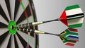 Flags of the UAE and South Africa on darts hitting bullseye of the target. International cooperation or competition