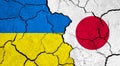 Flags of Ukraine and Japan on cracked surface
