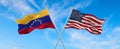 flags of USA and Venezuela waving in the wind on flagpoles against the sky with clouds on sunny day. Symbolizing relationship,