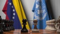 Flags of Venezuela and United Nations behind pawns on the chessboard. Conceptual editorial 3D rendering