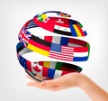 Flags of the world on a globe, held in hand.