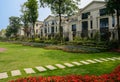 Flagstone paved path in grassy lawn to fenced houses on sunny summer day