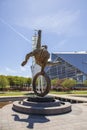 The Flair Olympic Statue in Georgia International Plaza with lush green trees and grass and a gorgeous clear blue sky