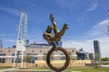 The Flair Olympic Statue in Georgia International Plaza with lush green trees and grass and a gorgeous clear blue sky