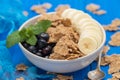 Flakes with blueberries and banana on brown bowl on blue background Royalty Free Stock Photo