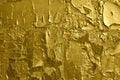 Rough texture of the old weathered cracked peeling golden graffiti paint on concrete wall. Vintage gold background.
