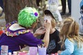 Flamboyant colorful woman painting faces of children at carnival