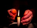 The flame of a burning wax candle in the hands of an old man Royalty Free Stock Photo