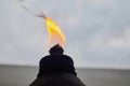 orange flame and burning wick on an oil torch against an overcast sky in the backyard