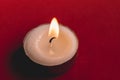 Flame candle on a red surface. Wallpaper.