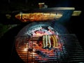 Flame grilled salmon, a traditional Nordic dish, and sausages on fire bowl, at night. Aerial view.