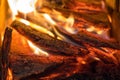 Flame incinerates firewood and transforms it ashes, close up, shallow depth of field. Blaze in a large stove. Nature