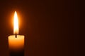 Flame of one white burning brightly wax  candle on the dark black background . Mourning candle. Isolated, close up. Lighting a can Royalty Free Stock Photo