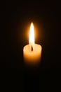 Flame of one white burning brightly wax  candle on the dark black background . Mourning candle. Isolated, close up. Lighting a can Royalty Free Stock Photo