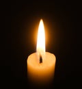 Flame of one white burning brightly wax  candle on the dark black background . Mourning candle. Isolated, close up. Lighting a can Royalty Free Stock Photo