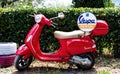 Flaming red vintage Vespa scooter parked for rent.