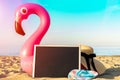 Flamingo isolated. Funny pink toy flamingo with blackboard, slippers and hat for text on summer ocean nature beach Royalty Free Stock Photo