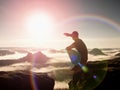 Flare. Lens defect, reflections. Man in sportswear is sitting on cliff's edge and looking to misty valley Royalty Free Stock Photo