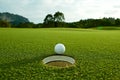 The flare lights photo of white golf ball near hole on fairway w Royalty Free Stock Photo