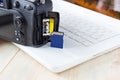 flash card in hand on camera and laptop background, memory card for SLR camera, flash drive, photo storage Royalty Free Stock Photo