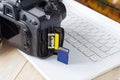 flash card in hand on camera and laptop background, memory card for SLR camera, flash drive, photo storage Royalty Free Stock Photo