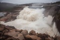 flash flood rushing through broken dam, with water spilling out of the reservoir