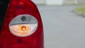 Flashing orange blinker light on rear lamp of car, close up view