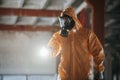 With flashlight. Man dressed in chemical protection suit in the ruins of the post apocalyptic building